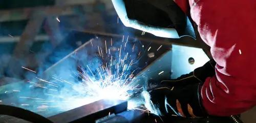 Welding process with bright arc sparks and operator in protective gear